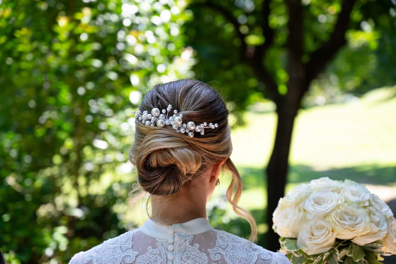 Acconciatura sposa raccolta con perle e bouquet di rose bianche